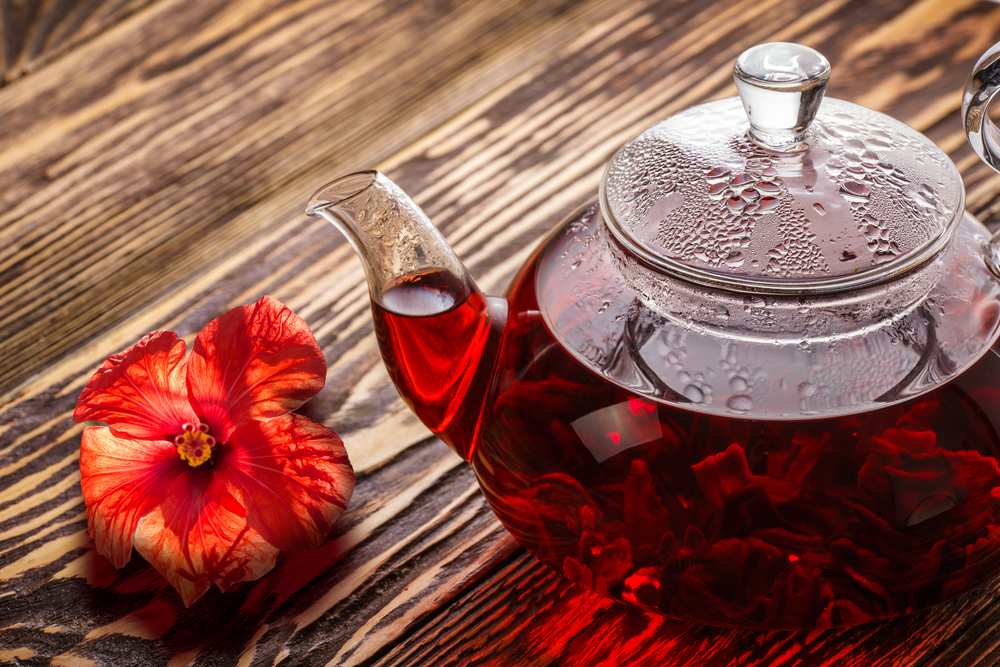 A teapot filled with hot tea is flavored with Hibiscus, giving it a deep red color and delicious flavor.